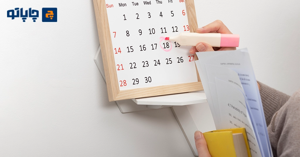 تصویر تقویم دیواری روی دیوار و خانم در حال خط کشیدن دور تاریخ مد نظر روی تقویم